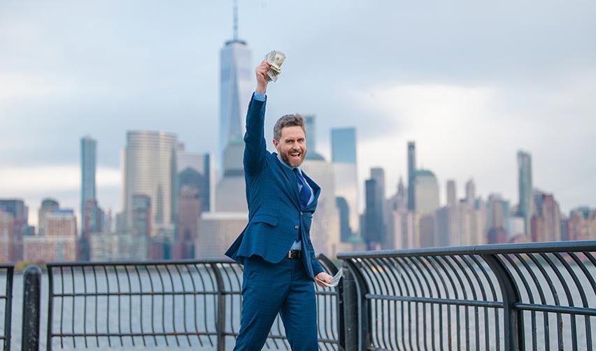 A happy U.S. permanent resident holding up a stack of money, celebrating the success of his own business.