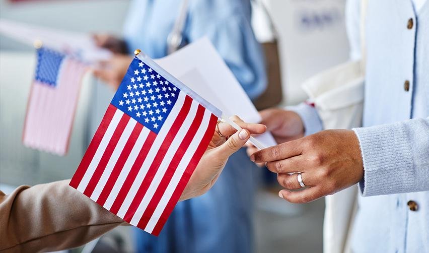 Two people holding a U.S. flag, symbolizing unity, safety, and government sponsored financial aid for permanent resident card holders.
