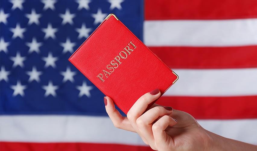 A US citizen holding a passport in front of the American flag.