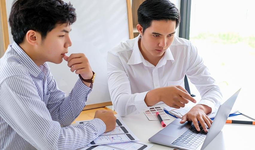 Foreign investors examining some sources on a laptop regarding investment capital or securities laws.