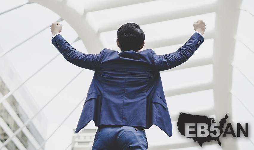 AN EB5 investors celebrating his lawful permanent residency with his arms in the air, with the EB5AN logo on the corner.