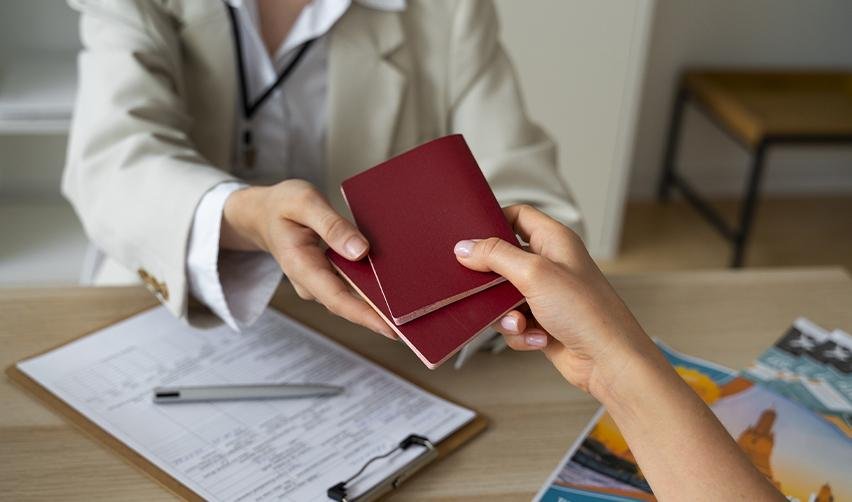 A foreign investor handing two passports to an immigration officer for form processing.