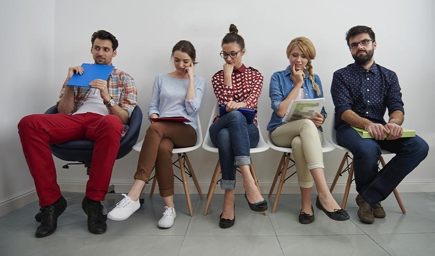 Green Card applicants sitting on chairs in a waiting room.