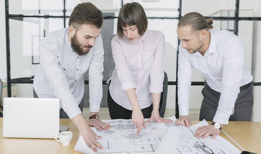 A team of regional center professionals reviewing blueprints in an office, highlighting due diligence and strong project planning as essential steps to avoid EB5 project delays.