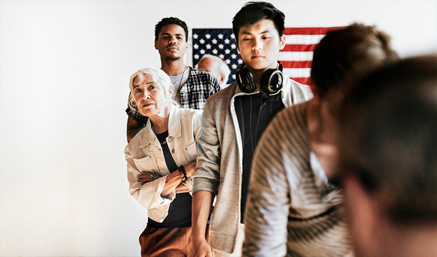 Immigrants waiting in line for U.S. visa processing with an American flag in the background—understanding EB5 visa eligibility and application steps.