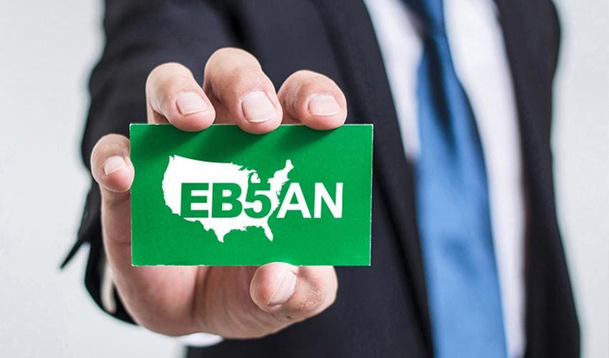A close-up of a regional center industry professional holding a green card with the EB5AN logo on it.