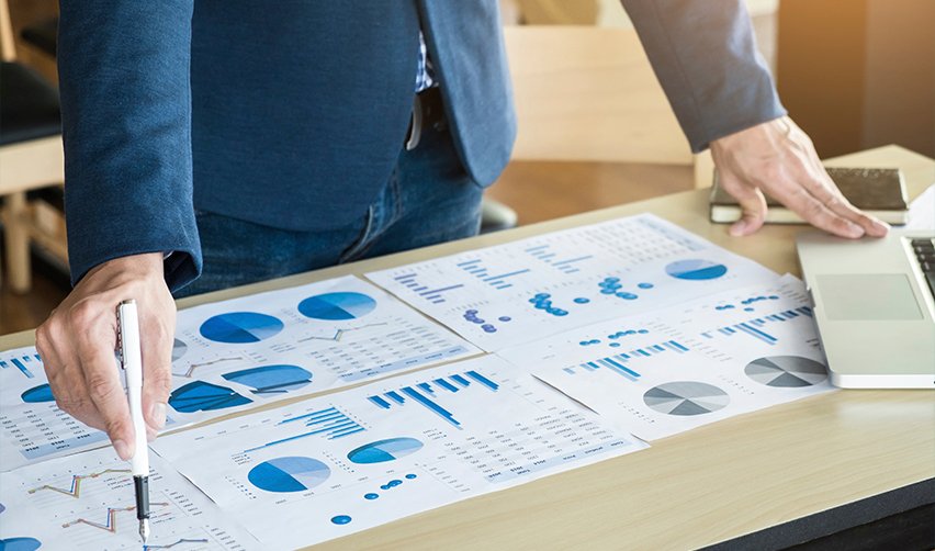 Professional analyzing financial graphs on a desk, preparing EB5 regional center project investment strategy and assessing job creation potential in targeted employment areas.