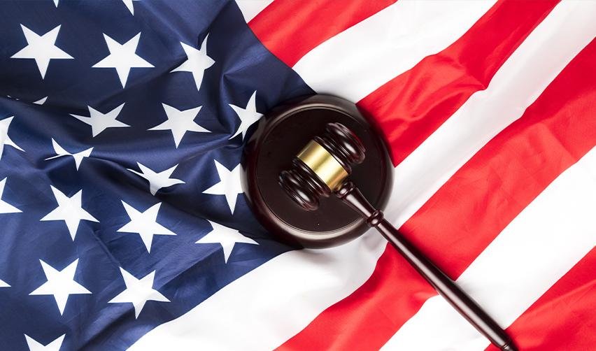 Judge’s gavel resting on an American flag, symbolizing legal protections and responsibilities of U.S. residents and citizens.