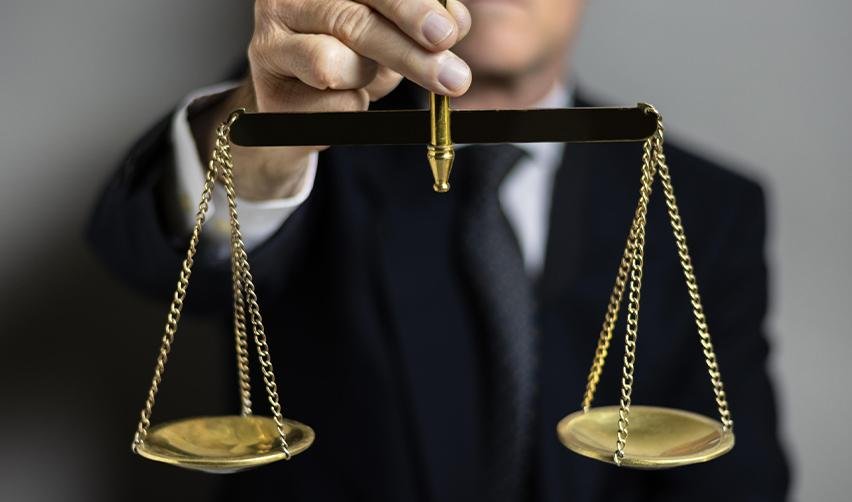 A businessman in a suit holding balanced scales, representing regulatory compliance and fairness in EB5 investment and redeployment rules.