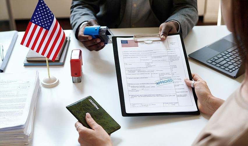 An immigration lawyer or a national visa center official handing a permanent green card application to an EB-5 investor.
