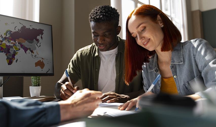 Two international students filling out different visa application forms after their F1 application is rejected.