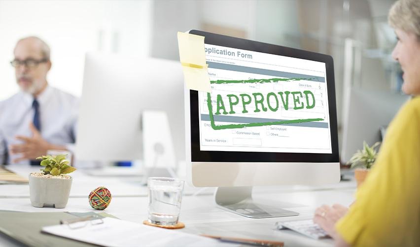 An EB5 investor looking at an approved sign of her visa application on a computer. She is obtaining a green card by creating jobs with the EB5 lower capital investment amount.