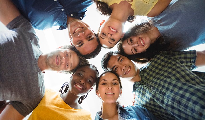 A diverse group of smiling international students looking down, highlighting the EB5 program's accessibility to individuals from all nationalities and backgrounds.