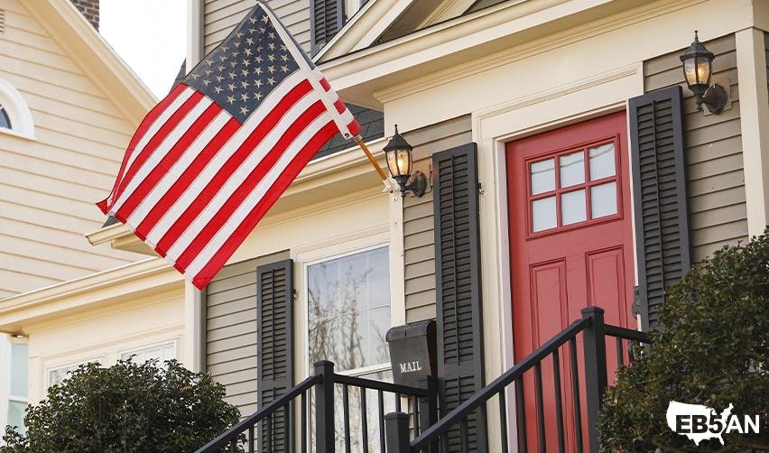 The EB5AN logo and an American flag displayed on a residential house, symbolizing the journey to US citizenship through the EB5 visa program.