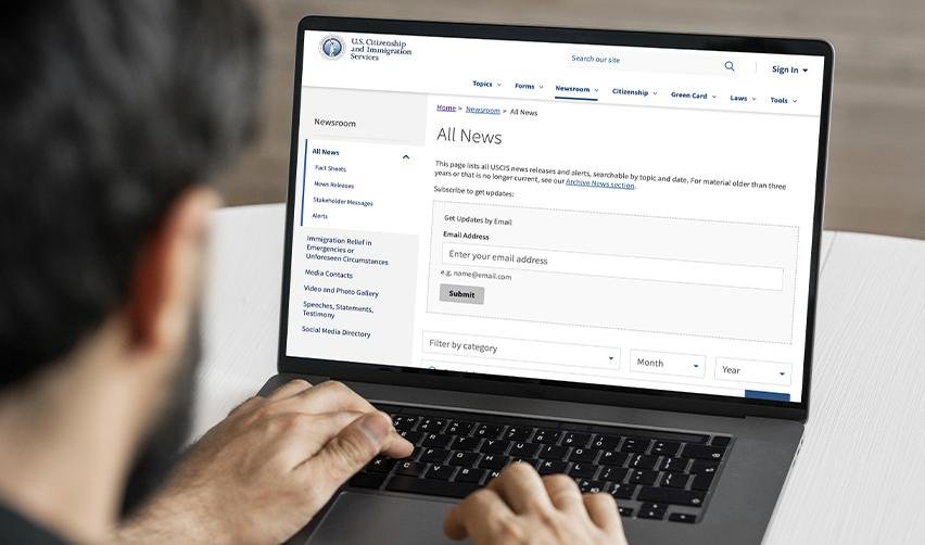 Investor reviewing the USCIS news page on a laptop, highlighting the importance of staying updated on EB5 policy changes and visa processing times.