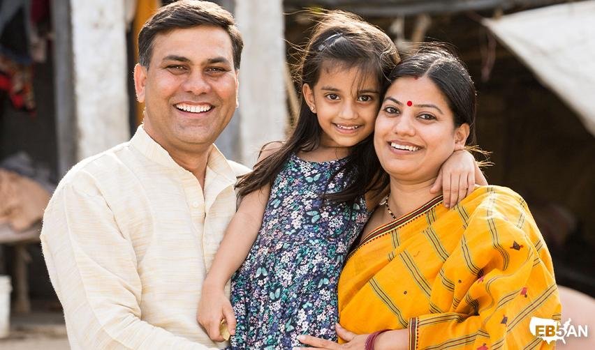 Indian parents with young daughter smiling outside with the EB5AN logo on the corner, highlighting family unity and the importance of timing in the EB5 immigration process.